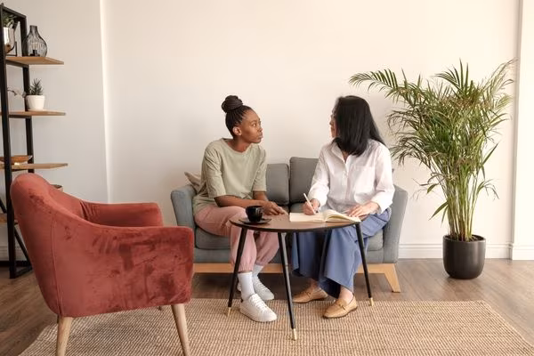 Two people sitting and talking during a therapy session in a bright, calm room