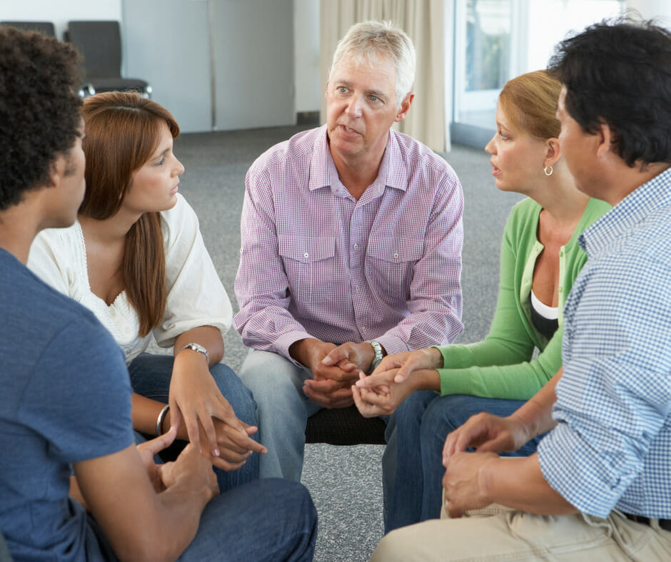 A group of people in a residential treatment center discussing their experiences with addiction