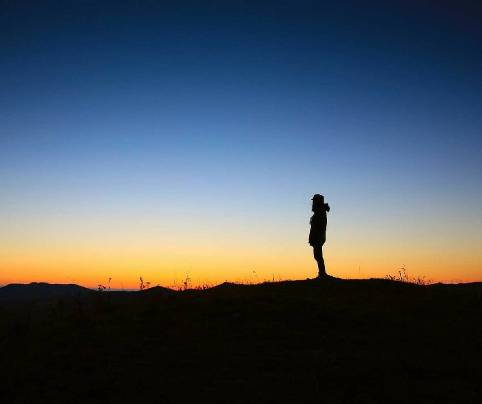 A person looking at a sunset, symbolizing the need for coping strategies to prevent emotional relapse
