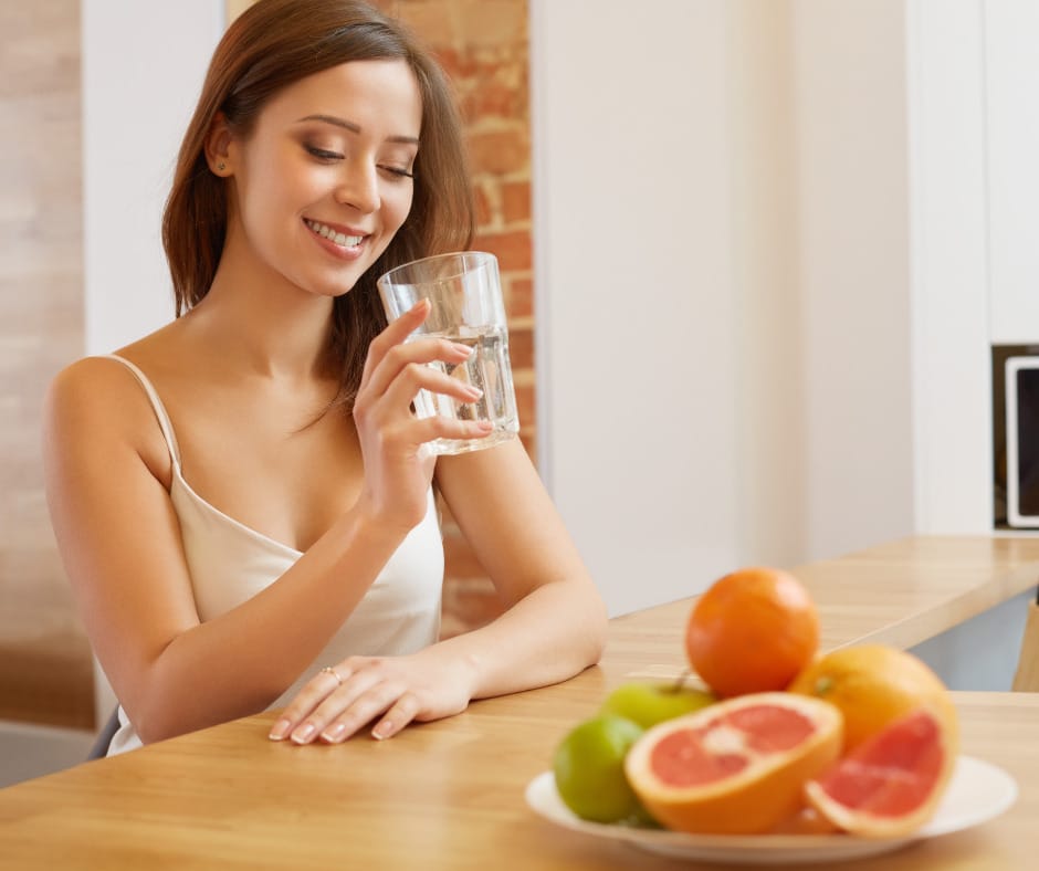 A person drinking a glass of water and eating healthy food